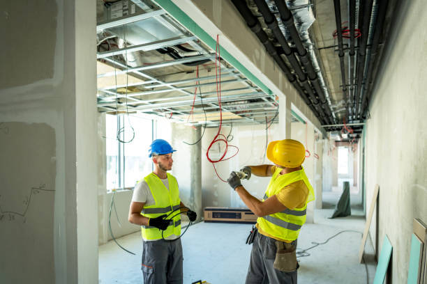 Side view at two construction crew workers separated by wall while renovating house, copy space. portrait of young people electrician connecting cables in wires cabinet while renovating house, copy space