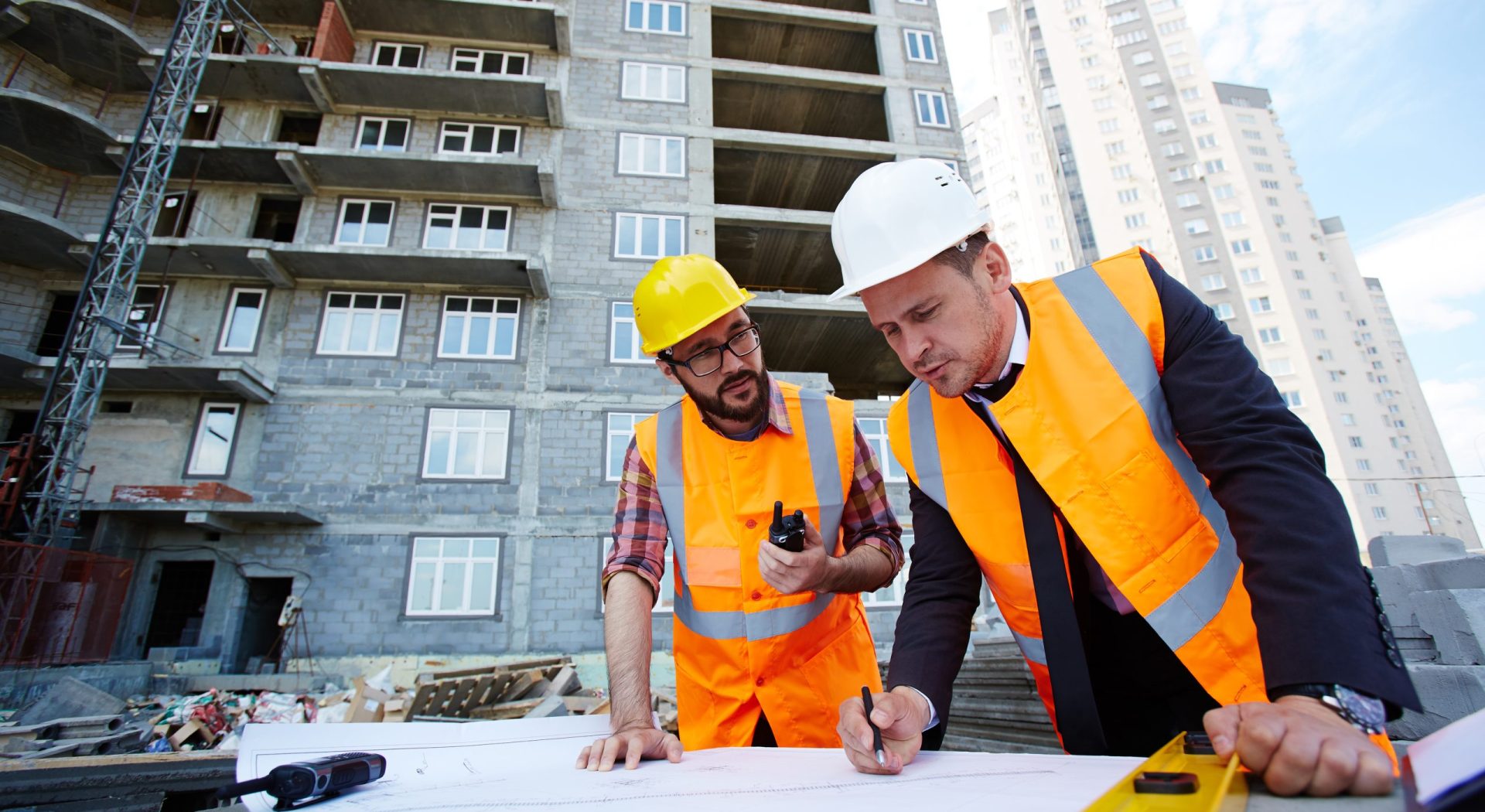 Modern engineer pointing at sketch in blueprint while explaining it to colleague